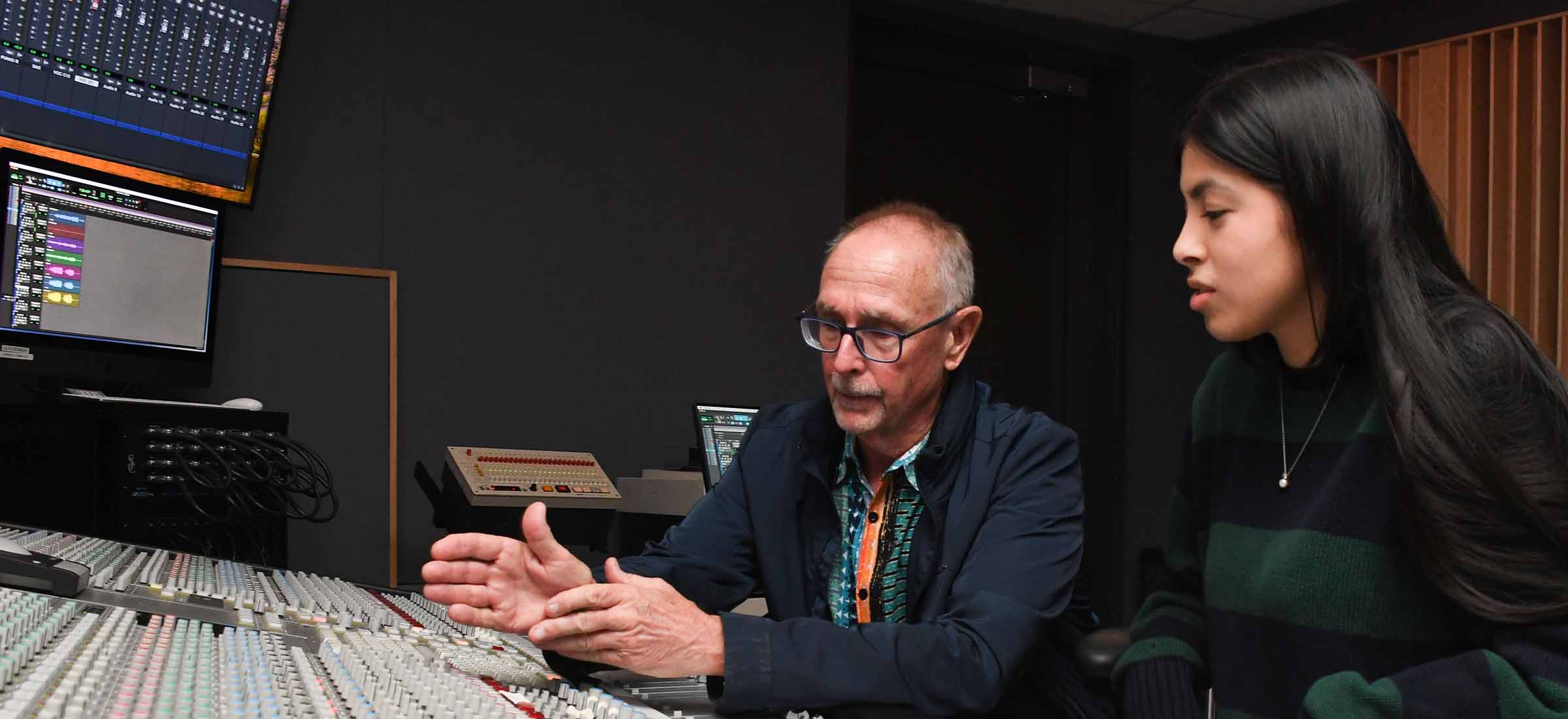 Audio engineering student with instructor on soundboard