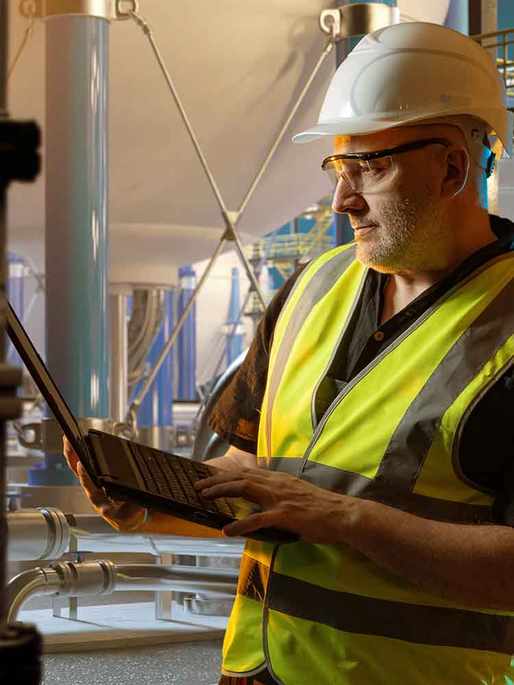 Man in hard hat working on computer.